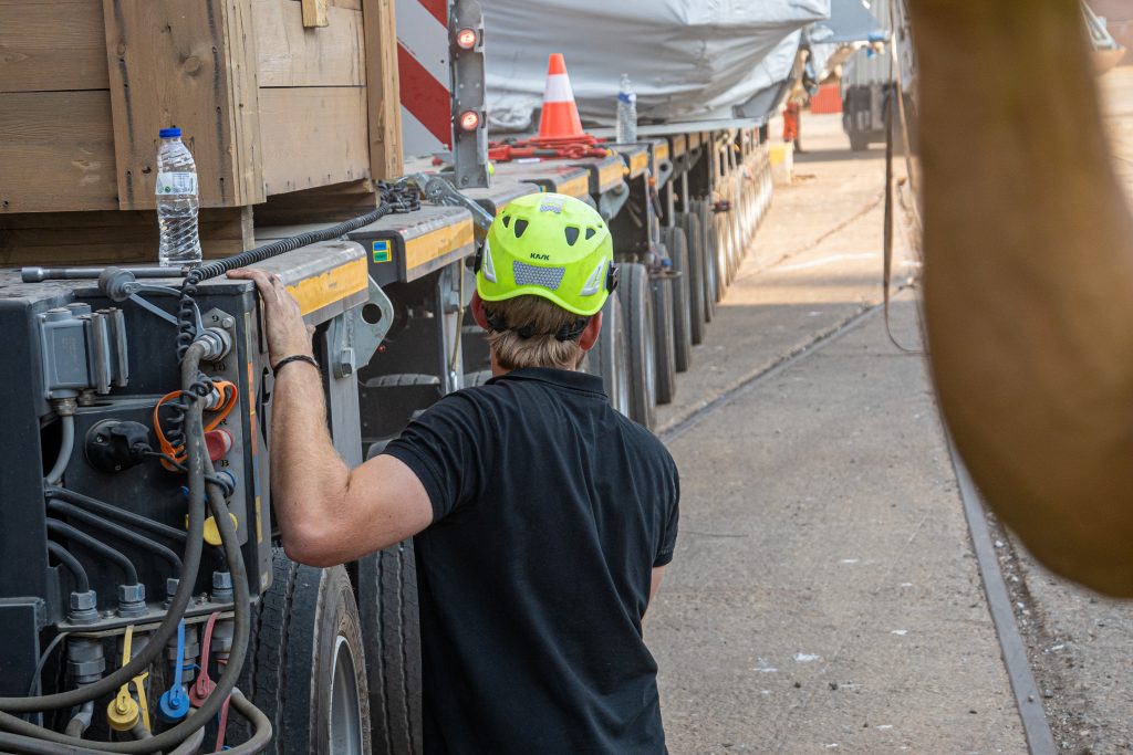 Mobile crane moving steel pipes at a shipping yard
